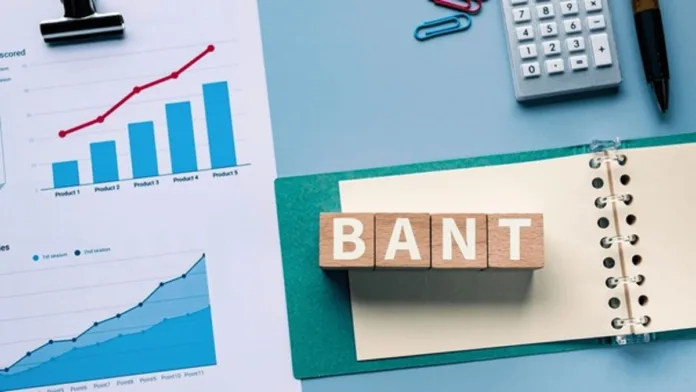 Office desk setup with sales charts, calculator, and notebook featuring wooden blocks spelling “BANT,” visually representing the concept of “Bent sales” strategy in business analytics.
