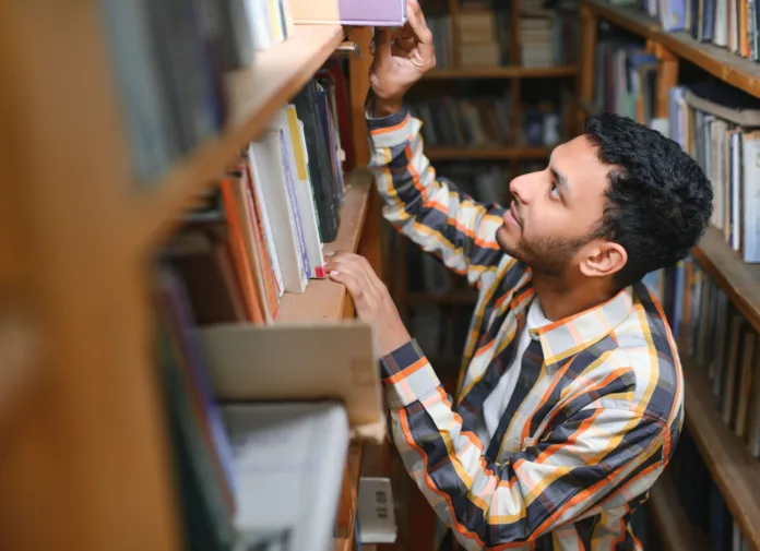 A person is looking for a book in a library.